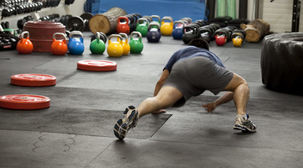 image of a man crawling on the floor of a gym 