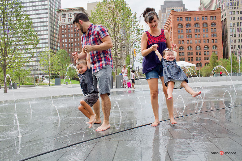 image of a young family playing in a sprinkler